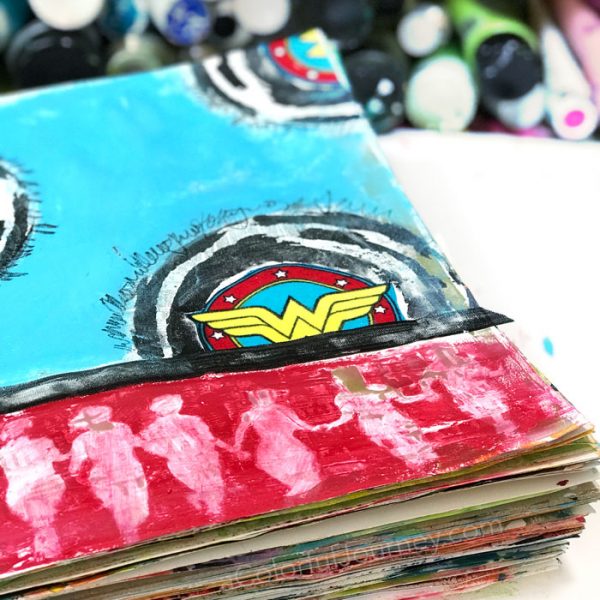 Playing in an art journal with Wonder Woman scraps and stencils and baby wipes by Carolyn Dube