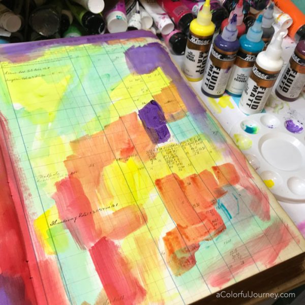 Splattering Pam Carriker paints and a quick stenciled title in a vintage art journal video by Carolyn Dube