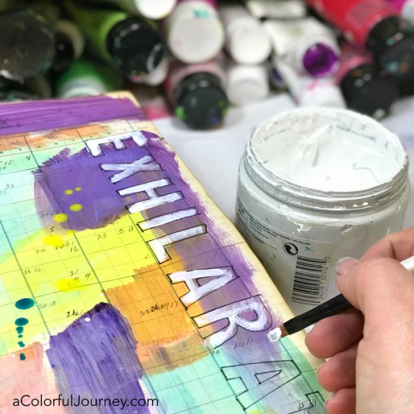 Splattering Pam Carriker paints and a quick stenciled title in a vintage art journal video by Carolyn Dube