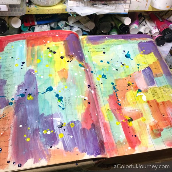 Splattering Pam Carriker paints and a quick stenciled title in a vintage art journal video by Carolyn Dube